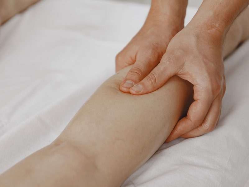 Sportmassage: beide Hände umfassen und kneten die Wadenmuskulatur