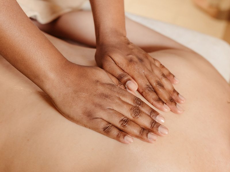 Wellness-Massage: ruhige, flächige Handbewegung über den geölten Rücken